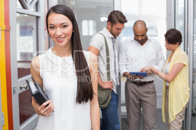 Smiling woman holding agenda in front of her colleague