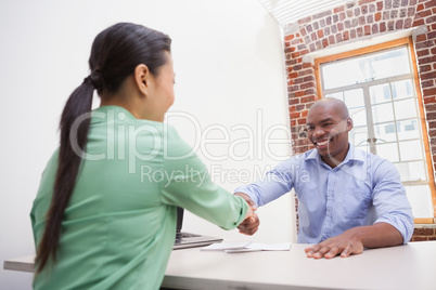 Casual business people shaking hands at desk