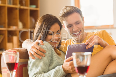 Young couple cuddling on the couch with tablet pc