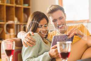 Young couple cuddling on the couch with tablet pc