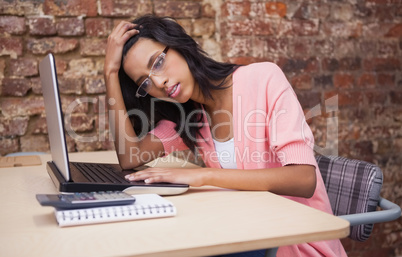 Troubled woman sitting at her desk with a laptop