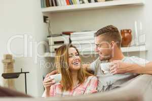 Cute couple relaxing on couch with coffee