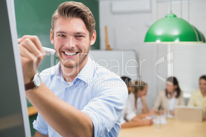 Smiling businessman writing on whiteboard with marker