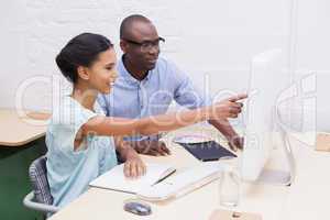 Woman showing something to her colleague on the laptop