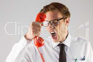 Angry geeky businessman holding telephone