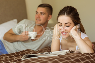 Cute couple reading newspaper in bed