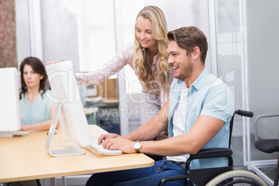 Casual businesswoman helping colleague in wheelchair