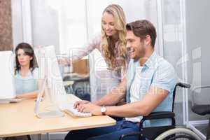 Casual businesswoman helping colleague in wheelchair