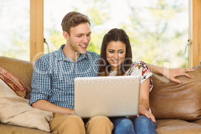 Young cute couple relaxing on couch with laptop