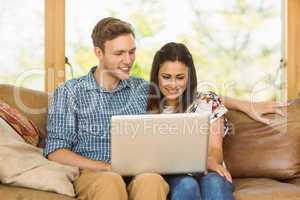 Young cute couple relaxing on couch with laptop