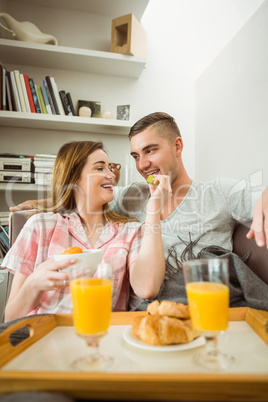 Cute couple relaxing on couch with breakfast