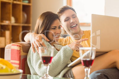 Young couple cuddling on the couch with laptop