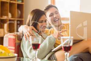 Young couple cuddling on the couch with laptop