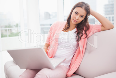 Pretty brunette using her laptop on the couch