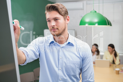 Focused businessman writing on whiteboard with marker