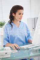 Brunette doctor using  mouse of computer