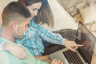 Cute couple relaxing on couch with laptop