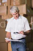 Manager looking through magnifying glass in warehouse