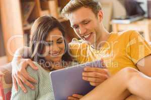 Young couple cuddling on the couch with tablet pc