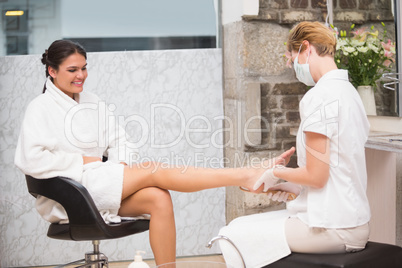 Woman getting a pedicure from beautician