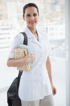 Smiling doctor holding medical books