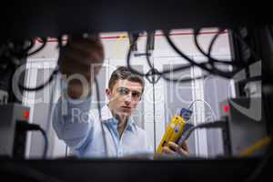 Technician using cable tester while fixing server