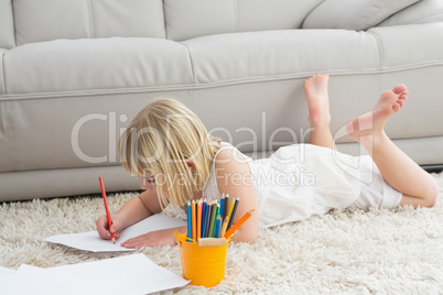 Smiling litlle girl drawing lying on the floor