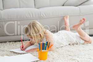 Smiling litlle girl drawing lying on the floor