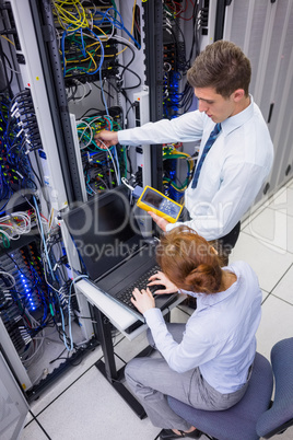 Team of technicians using digital cable analyser on servers