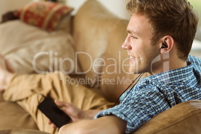 Young man listening to music on his couch