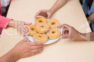 Business team reaching for doughnuts on table