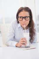 Pretty businesswoman drinking milk at her desk