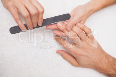 Manicurist filing a customers nails