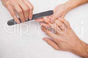 Manicurist filing a customers nails
