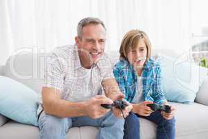 Son and father playing video games together on the couch