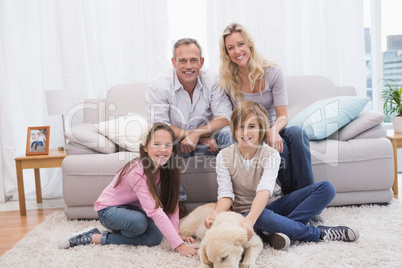 Smiling family with their pet yellow labrador on the rug