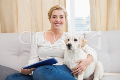 Happy blonde using tablet pc with puppy