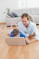 Casual father and son using laptop on the floor