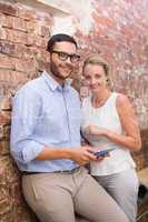 Business people text messaging against brick wall