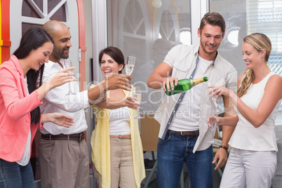 Man pouring champagne into the glass of his colleagues