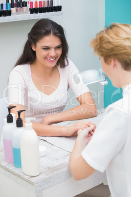 Pretty nail technician giving manicure to customer