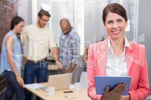 Smiling woman holding tablet in front of her colleague