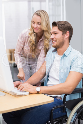 Casual businesswoman helping colleague in wheelchair