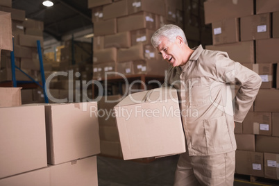 Worker with backache while lifting box in warehouse