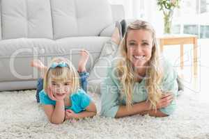 Smiling daughter and mother laying on the floor