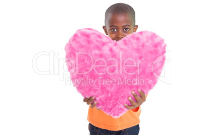 Cute boy showing pink heart pillow