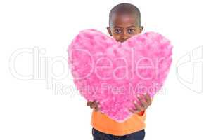 Cute boy showing pink heart pillow