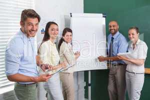 Casual business team having a meeting smiling at camera