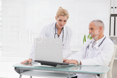 Concentrated doctors coworker using laptop