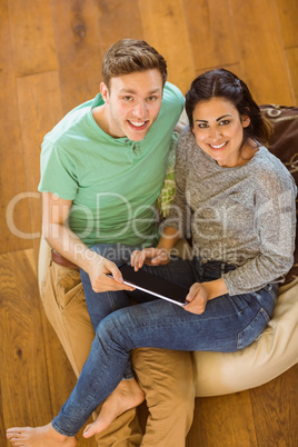 Cute couple using tablet pc on beanbag